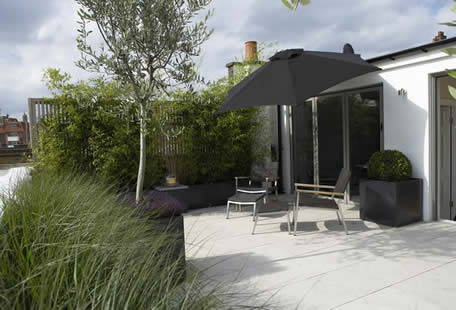 Modern roof deck with black pergola, outdoor seating, potted plants, and paved patio.