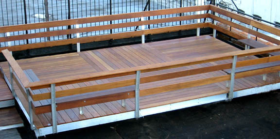 Wooden roof deck with metal railings and open-air design.