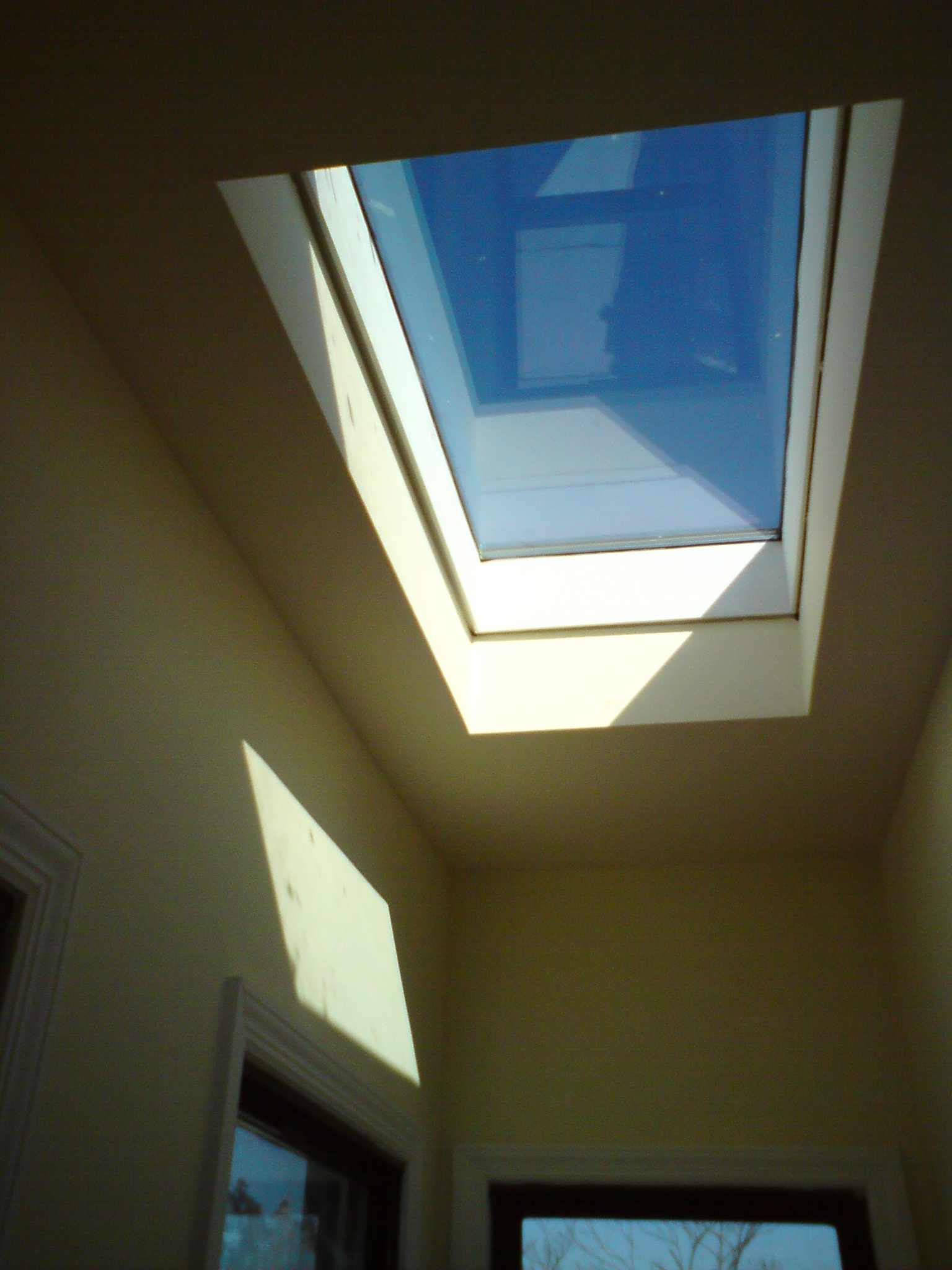 Interior view of a skylight window in ceiling with blue sky visible through glass pane