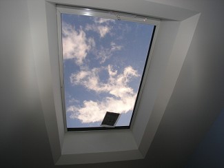 View of blue sky with white clouds through a rectangular skylight window