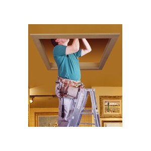 Worker on ladder installing or repairing ceiling fixture against yellow wall