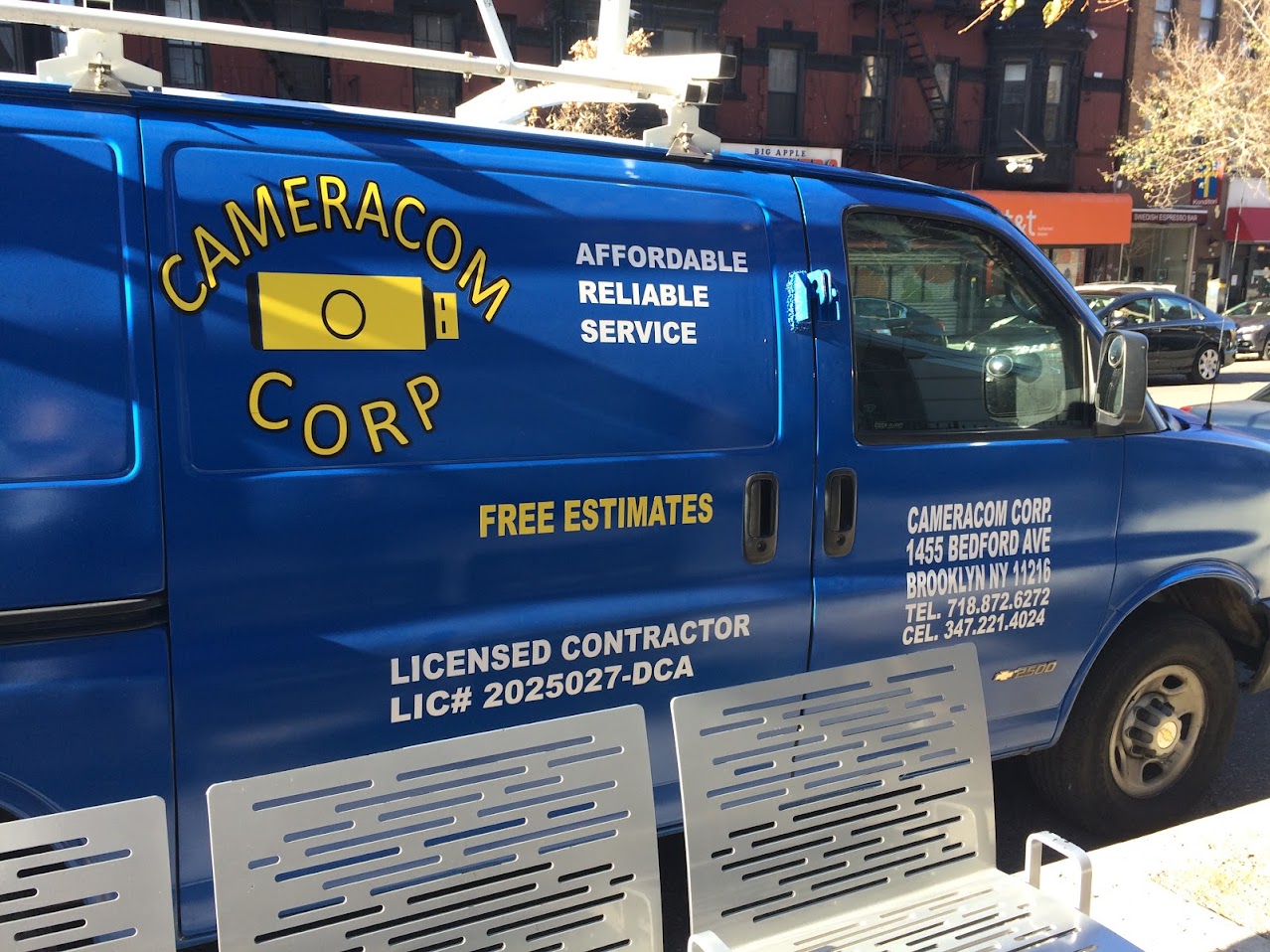 Blue service van with yellow lettering for Cameracom Corp, displaying contact information and licensed contractor license number.