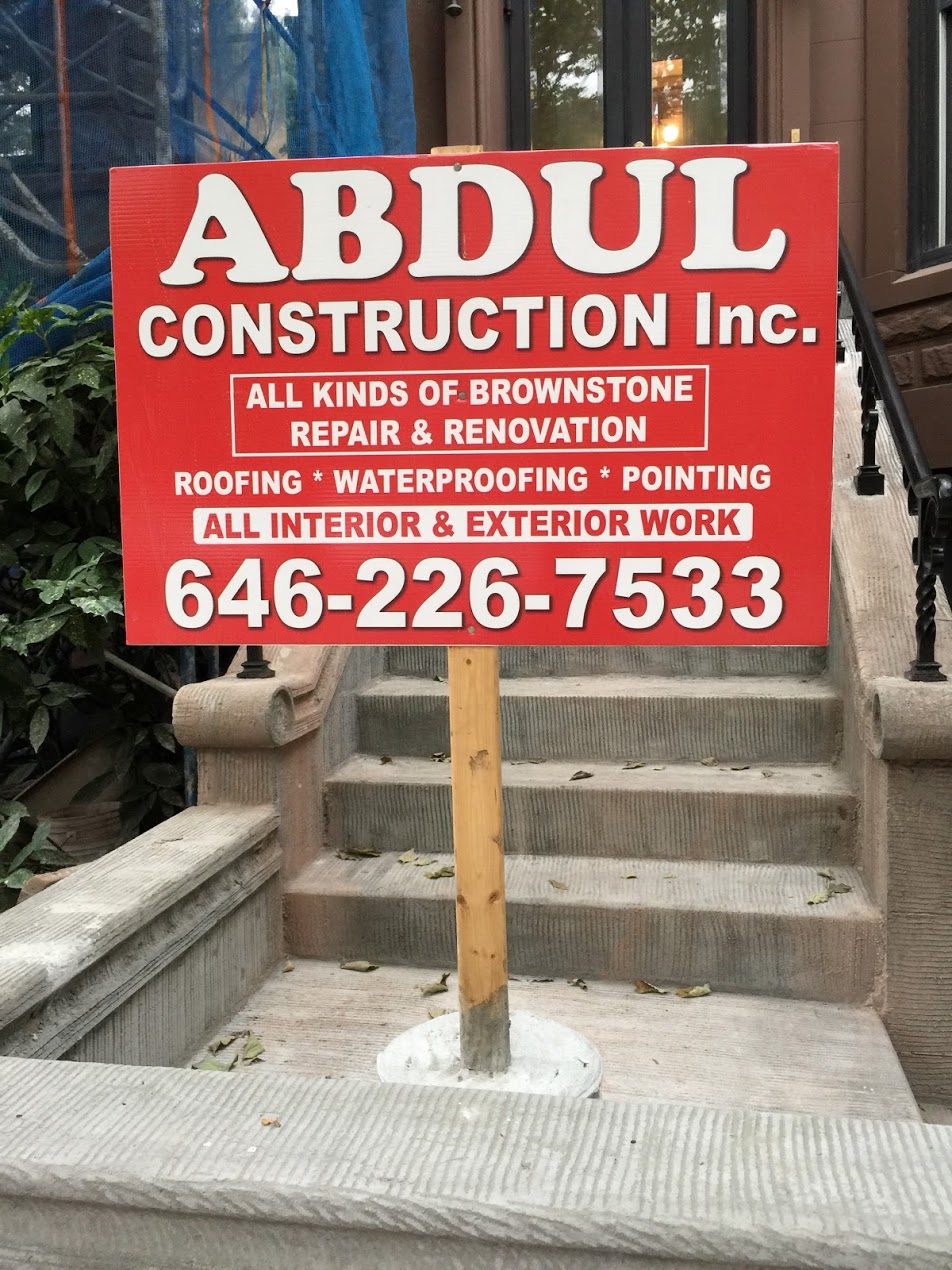 Red construction company sign for Abdul Construction Inc advertising roofing and brownstone repair services