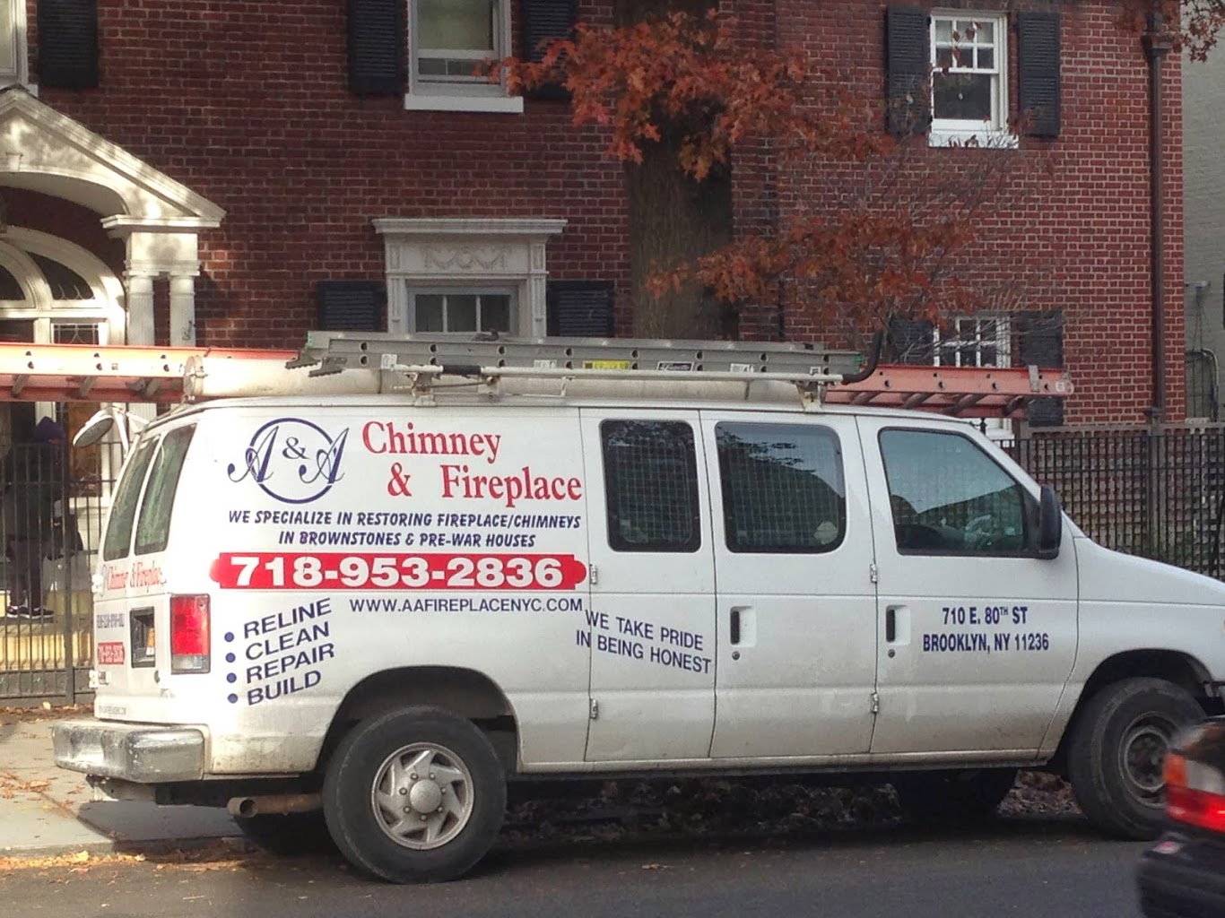 White service van with chimney and fireplace business branding parked in front of brick building