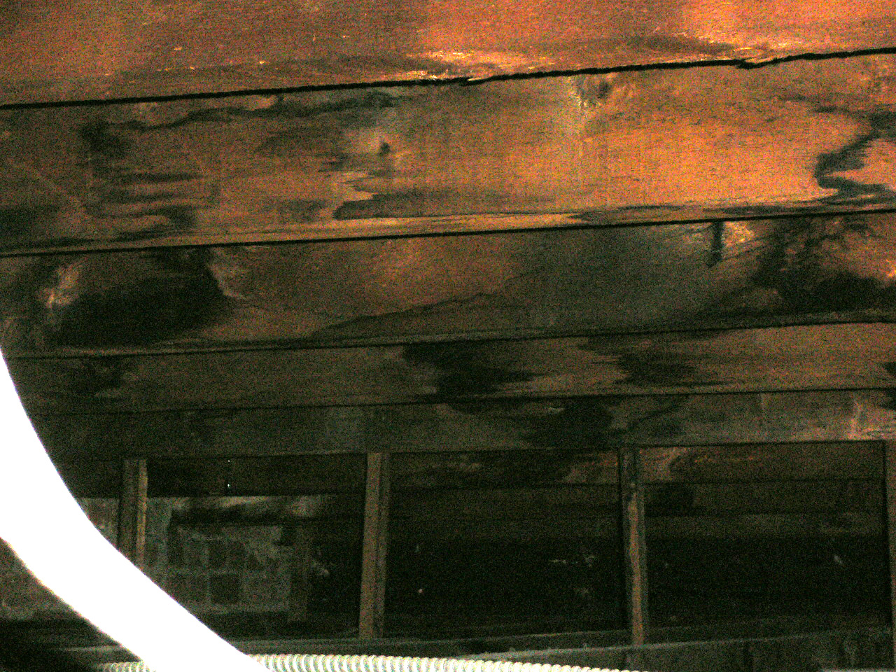 Rusted steel beam and wooden roof cavity structure showing heavy corrosion and decay.