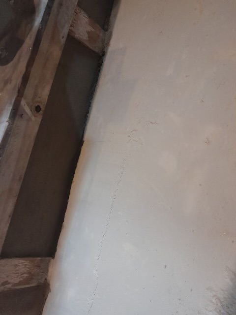 Concrete floor with wooden beam edge and visible gap during basement renovation work