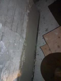 Unfinished basement concrete floor with construction materials and tools visible