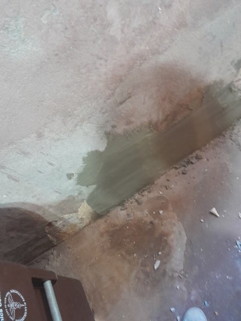 Basement concrete floor with patching compound and repair work in progress.