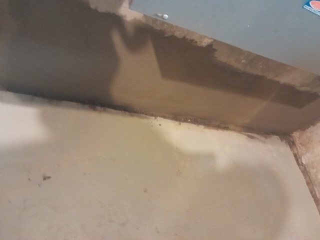 Overhead view of basement concrete floor under renovation with exposed wooden forms and beams.