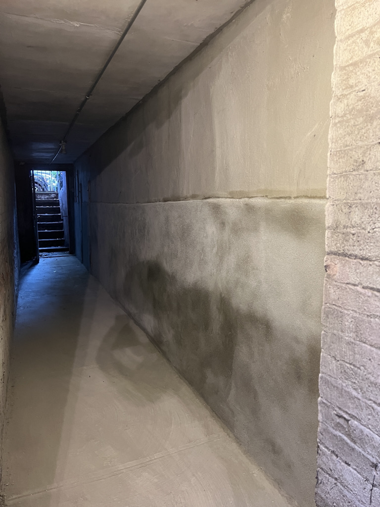 Long narrow hallway with newly finished drywall walls and brick on right side
